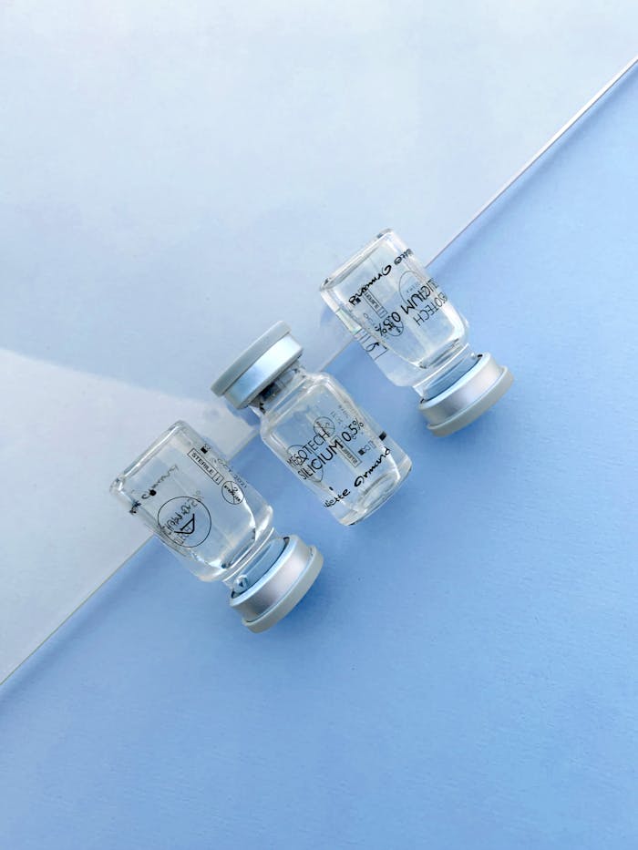A minimalist top view of transparent medical vials on a light blue surface. Perfect for healthcare content.