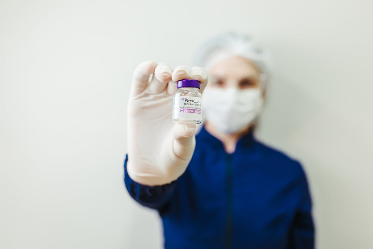 Services Healthcare worker holding a Botox vial in a clinical setting, wearing protective gear.