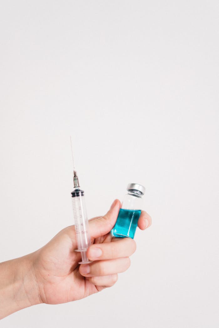 Services A hand holding a vaccine syringe and bottle against a white background.