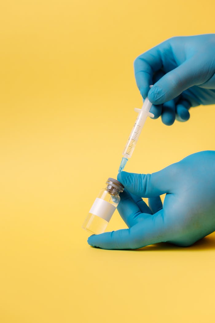 Services Close-up of gloved hands holding syringe and vial for vaccination.