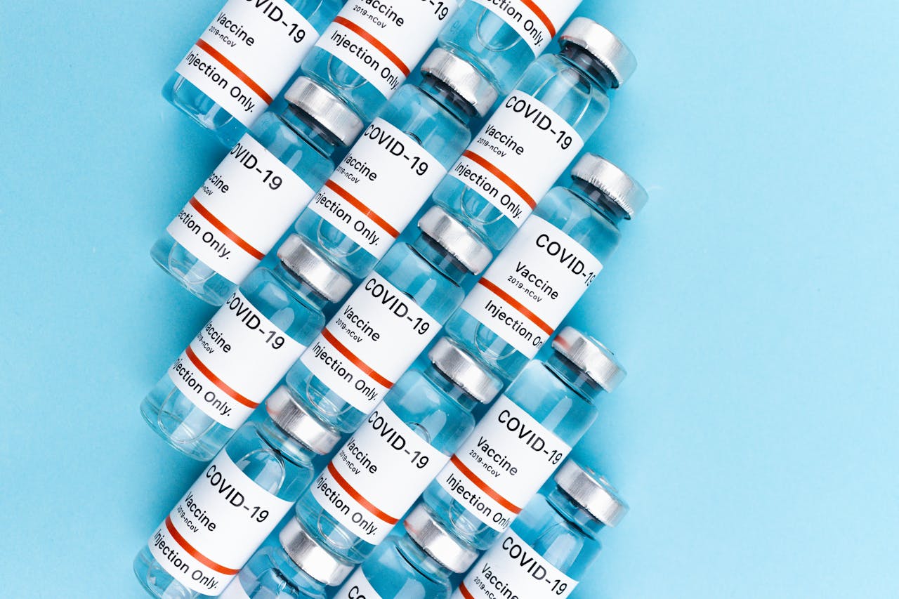 Services Top view of COVID-19 vaccine vials arranged on a blue surface, highlighting vaccination and pandemic themes.